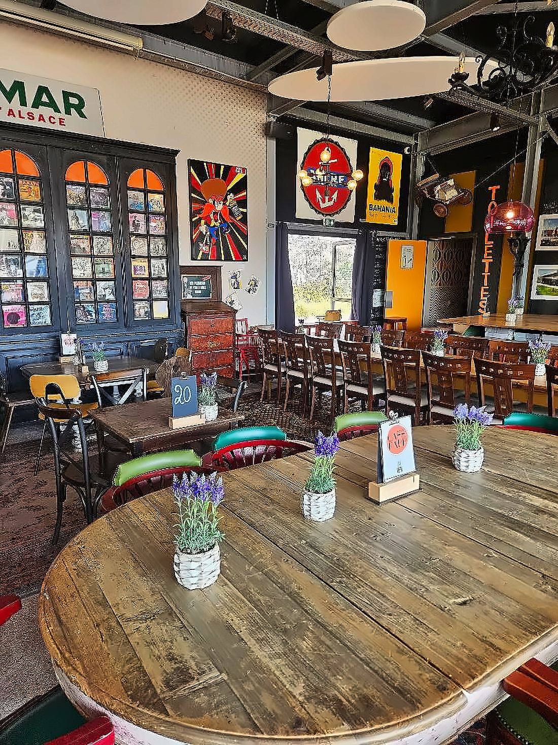 Salle intérieure du Restaurant Café Rapp : bibliothèque de vinyles, affiches vintage et longues tables en bois
